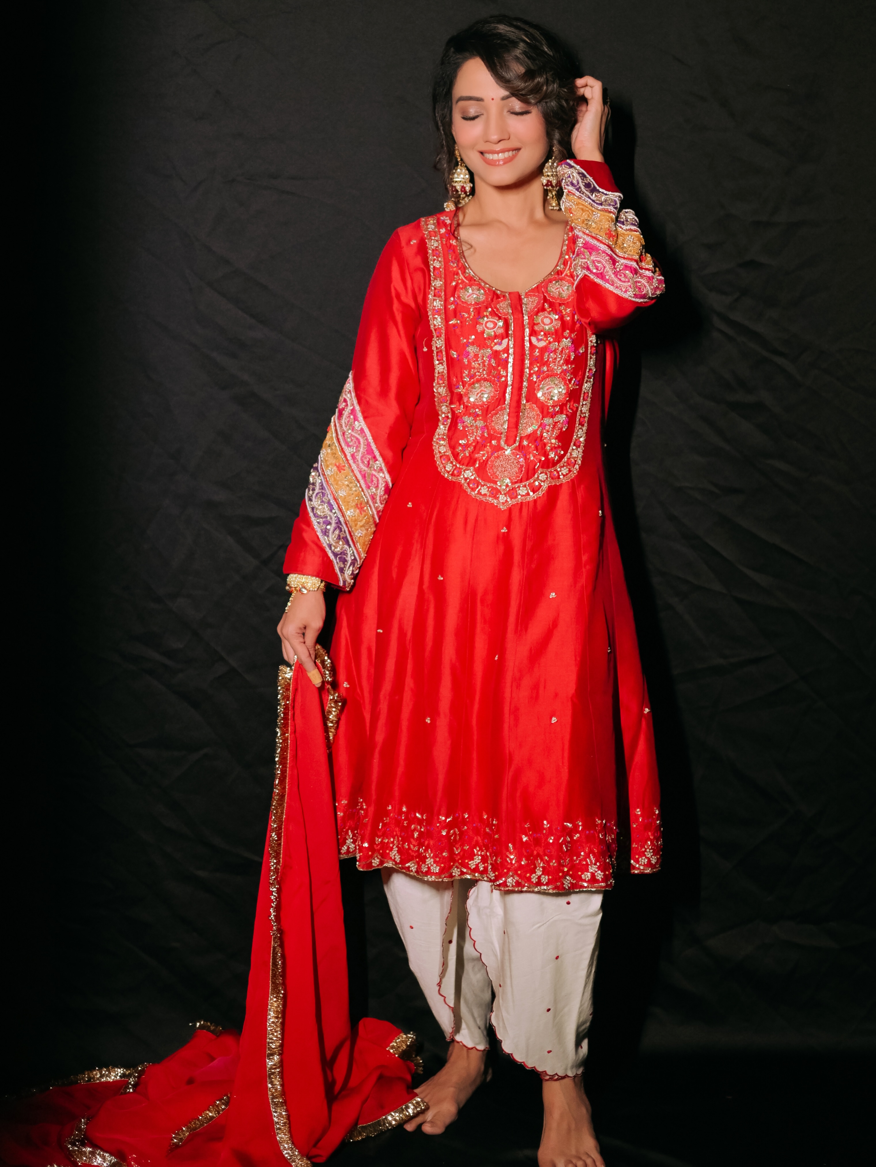 Adaa Khan completes the look with soft radiant makeup, subtly defined eyes, and a side-swept hairstyle adorned with floral accents that enhance the outfit's traditional charm.