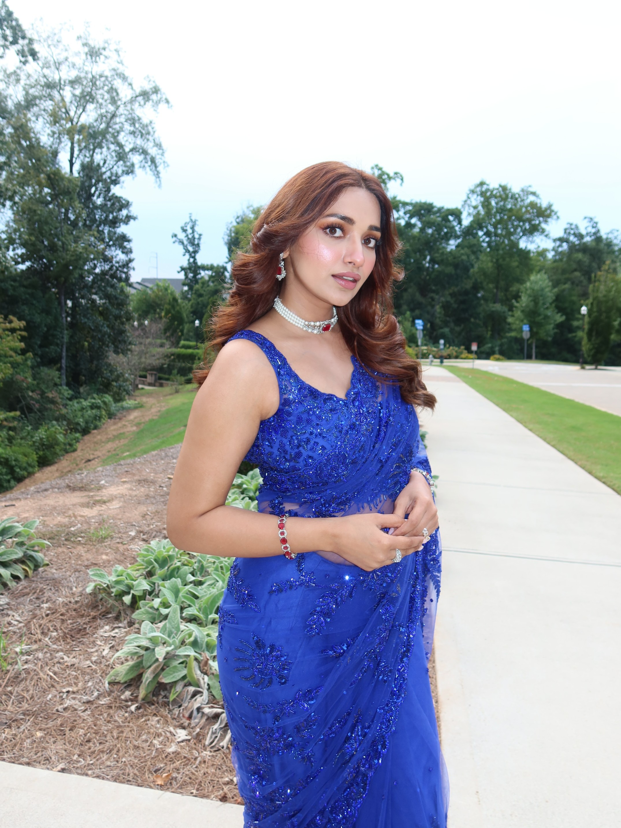 Jiya Shankar elevates the look with a diamond choker, matching earrings, dainty bracelets, and statement rings that perfectly complement the richly embellished saree.