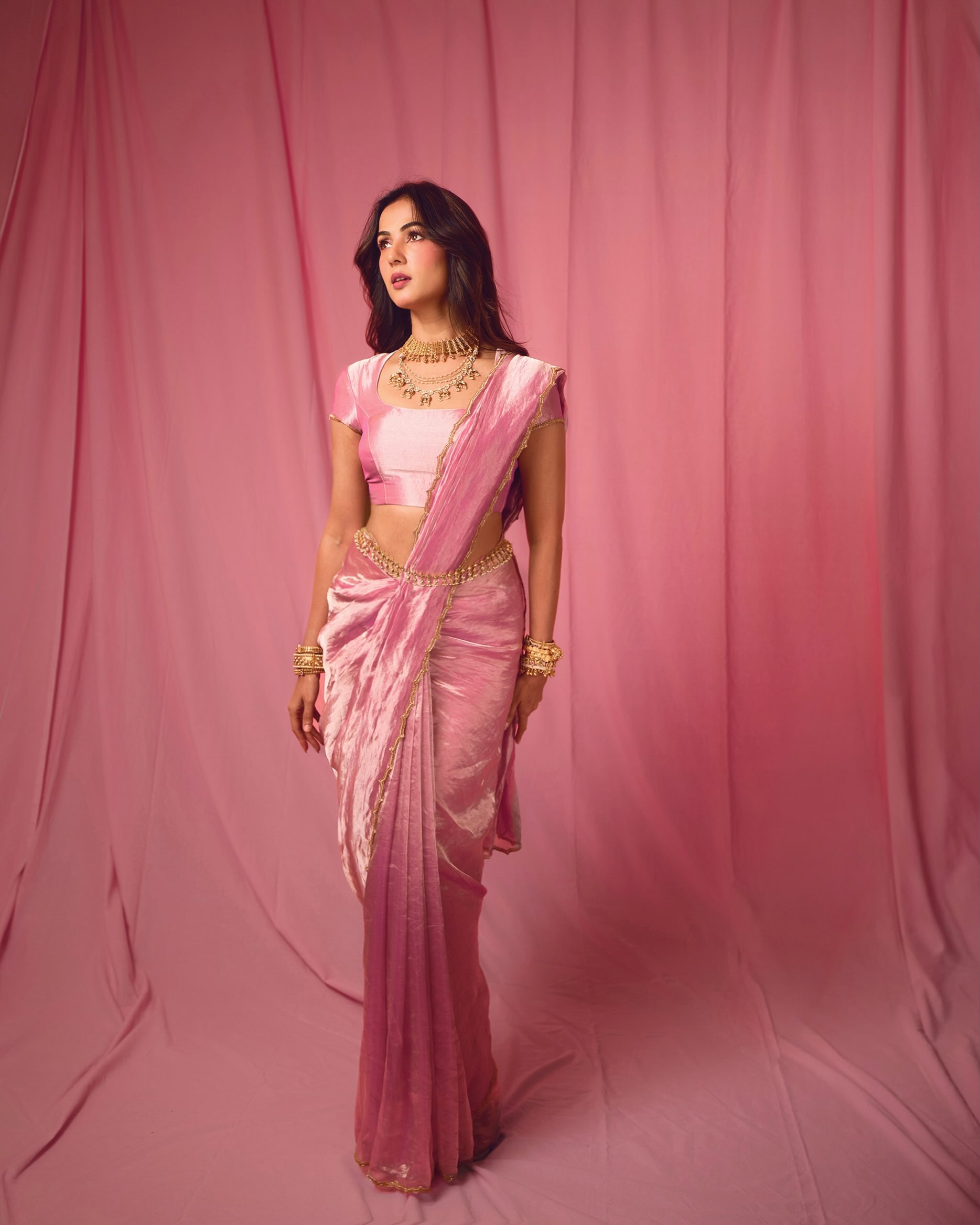 Sonal S Chauhan elevates the ensemble with layered statement necklaces, stacked bangles, delicate rings, and a chic waist chain that adds a touch of regal charm.