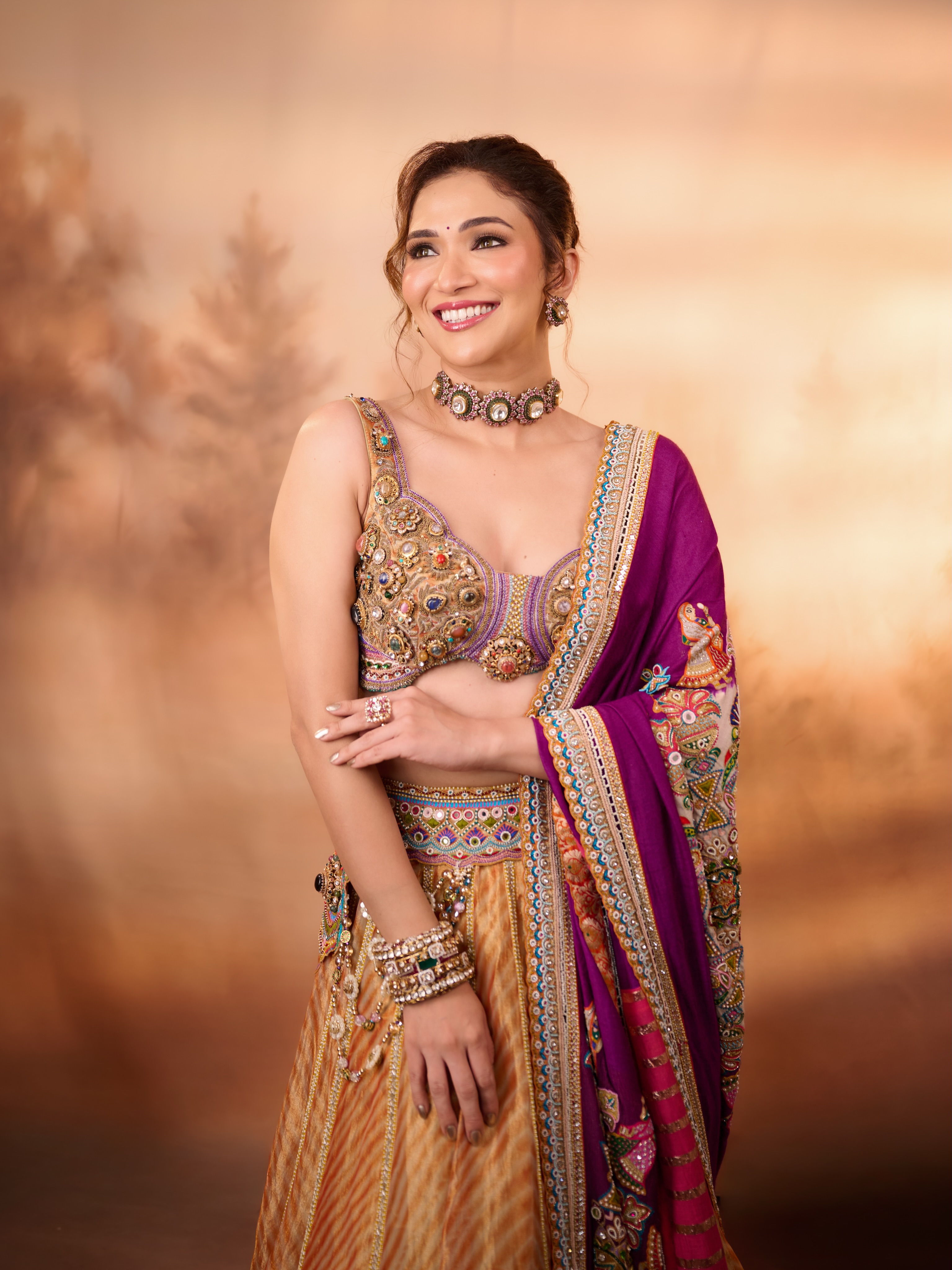 Ridhima Pandit complements the look with a statement choker, earrings, stacked bangles, rings, and a metallic round clutch.