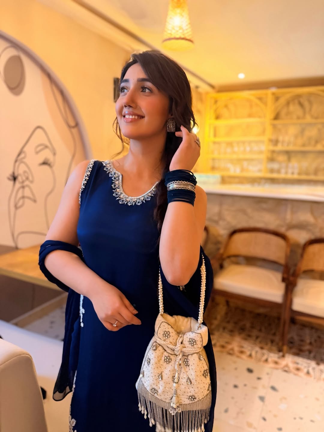 Ashnoor Kaur adds charm with an ivory potli featuring textured threadwork and soft contrast.