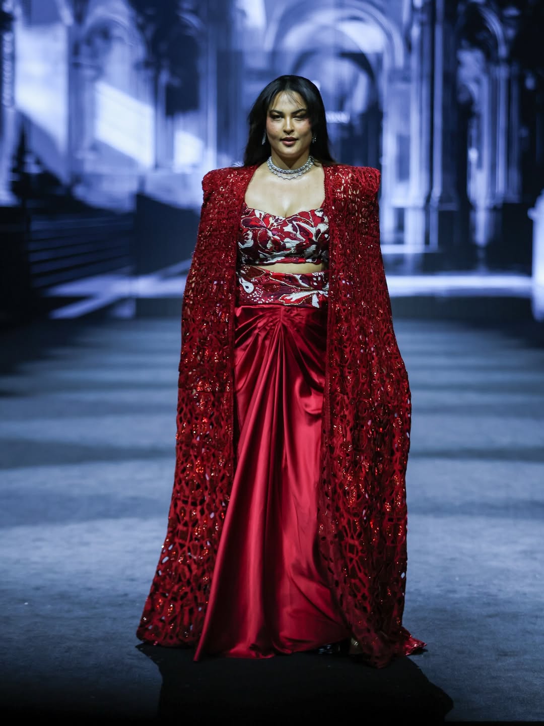 Sakshi Sindwani elevates the ensemble with a sleek choker that brings shine and balances the striking red palette.